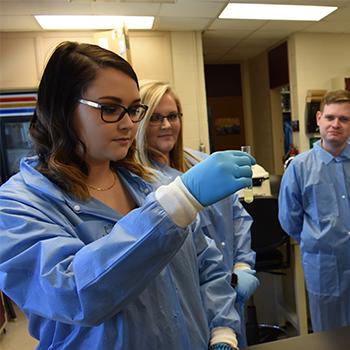 Med Lab Student looking at test tube with fellow student observing in the background